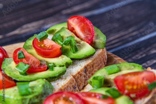 Avocado toast topped with tomato and green onion on a slice of carrot bread