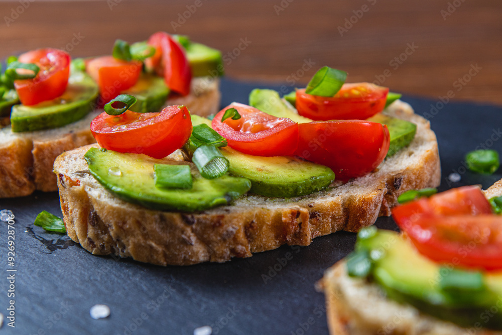 Avocado toast topped with tomato and green onion on a slice of carrot bread Avocado toast topped with tomato and green onion on a slice of carrot bread