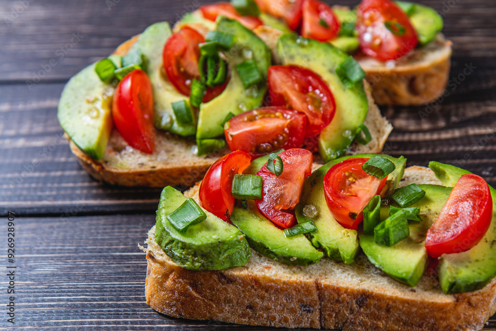 Avocado toast topped with tomato and green onion on a slice of carrot bread Avocado toast topped with tomato and green onion on a slice of carrot bread