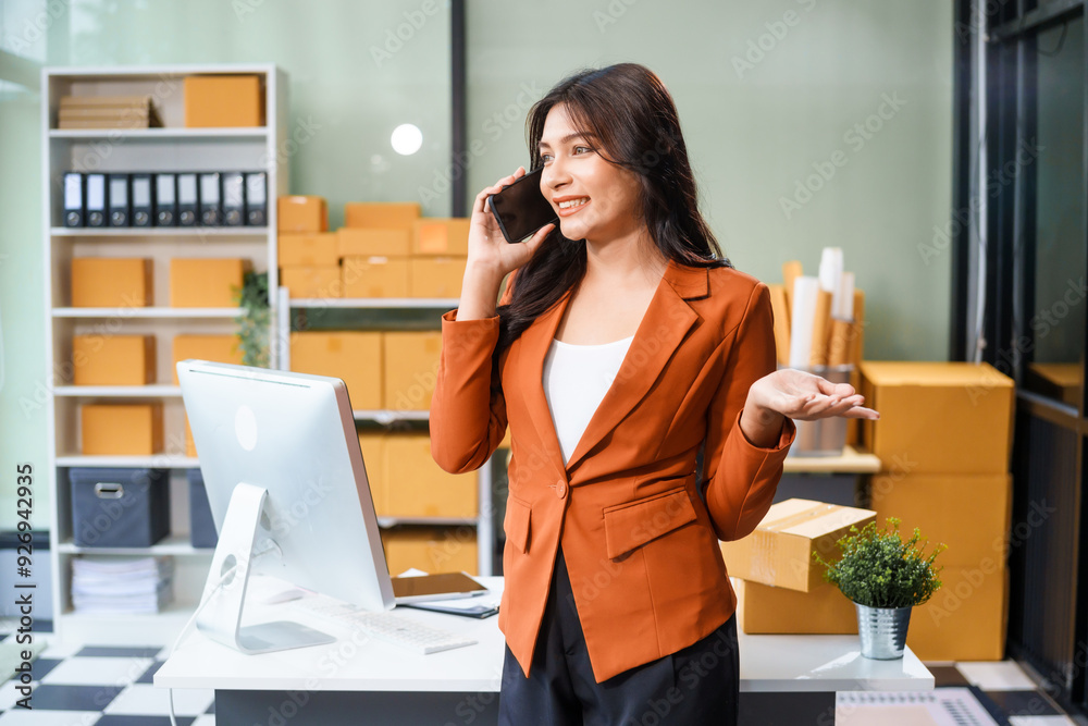 A beautiful businesswoman works at her desk, selling products online. She smiles while watching a tablet and talking on the phone. Her online business has exceeded sales targets, marking her success. A beautiful businesswoman works at her desk, selling products online. She smiles while watching a tablet and talking on the phone. Her online business has exceeded sales targets, marking her success.