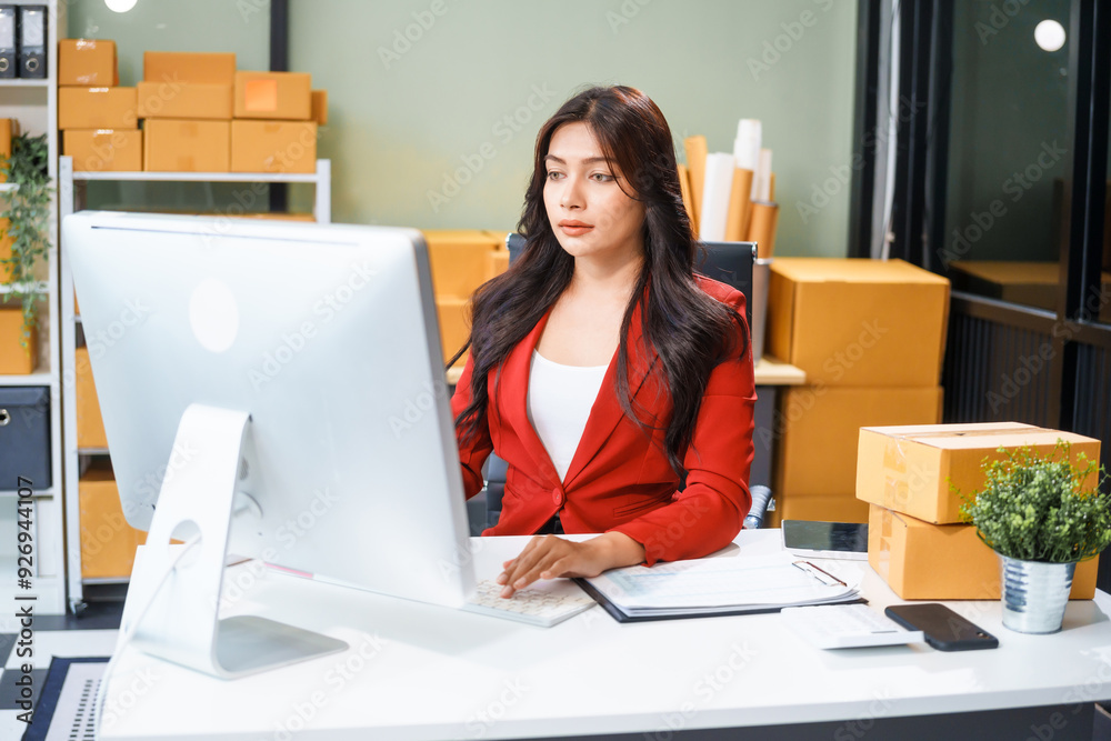 A beautiful businesswoman sits at the table, looking at the computer screen and talking on the phone. She analyzes marketing plans with a smile, feeling happy and successful in her online business. A beautiful businesswoman sits at the table, looking at the computer screen and talking on the phone. She analyzes marketing plans with a smile, feeling happy and successful in her online business.