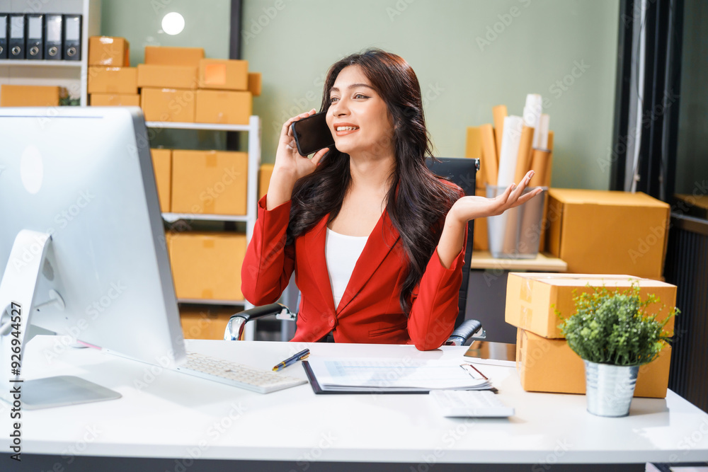 A beautiful businesswoman sits at the table, looking at the computer screen and talking on the phone. She analyzes marketing plans with a smile, feeling happy and successful in her online business. A beautiful businesswoman sits at the table, looking at the computer screen and talking on the phone. She analyzes marketing plans with a smile, feeling happy and successful in her online business.