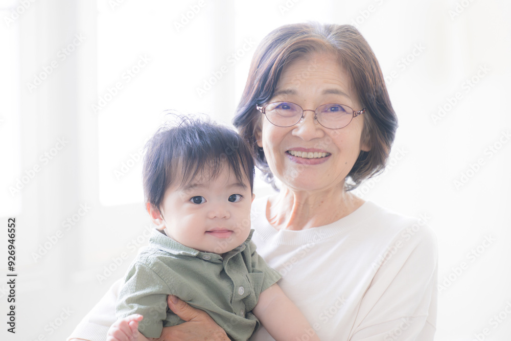 Senior woman holding her grandson, looking at the camera Image of a grandmothe Senior woman holding her grandson, looking at the camera Image of a grandmothe