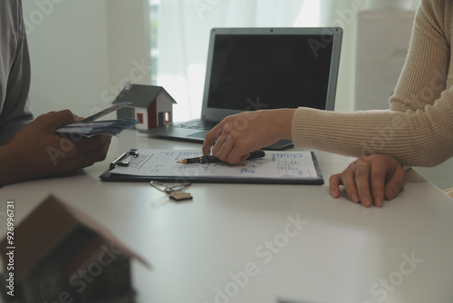 Real estate agent home sales broker is using a pen pointing to the house model and explains the business contract, rent, buy, mortgage, loan, or home insurance