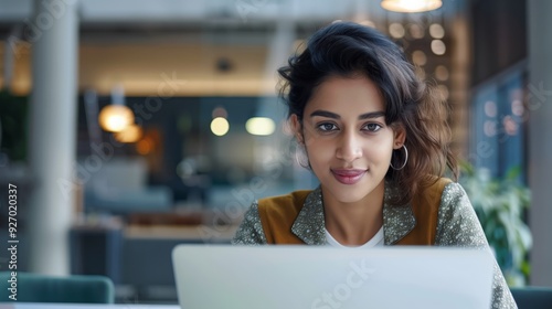 Editorial eyelevel shot of an attractive indian woman in her late thirties working on laptop inside modern office