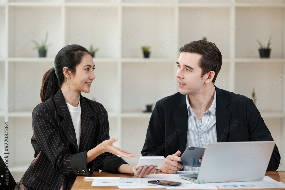 Two people in suits are talking in a room with a lot of plants Two people in suits are talking in a room with a lot of plants