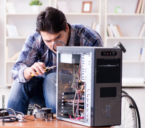 Disabled man on wheelchair repairing computer