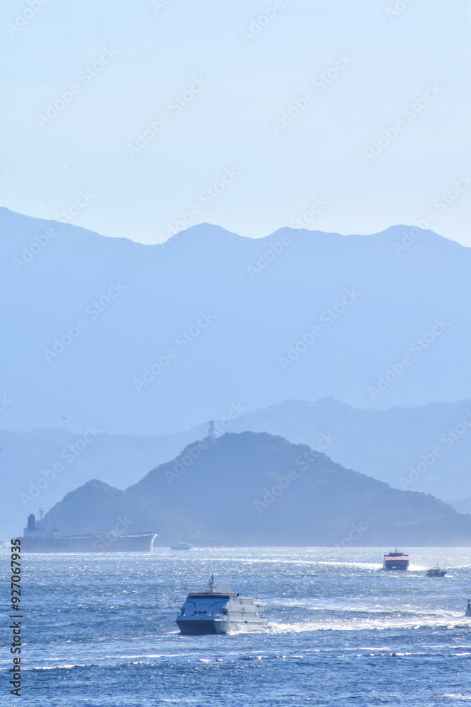 The view of the sea in the sunny day with blue sky and mountain and ships in the background. Calm sea and water. Sea background, wave pattern. Nature concept. The view of the sea in the sunny day with blue sky and mountain and ships in the background. Calm sea and water. Sea background, wave pattern. Nature concept.