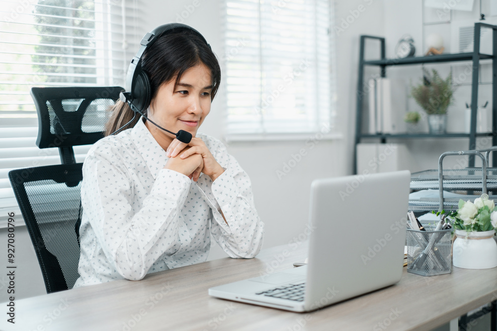 A focused woman wearing a headset works from home on her laptop in a modern office environment with natural light. A focused woman wearing a headset works from home on her laptop in a modern office environment with natural light.