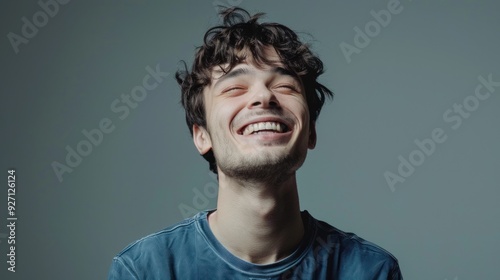 Young man showing joy with a big smile standing against a solid studio background