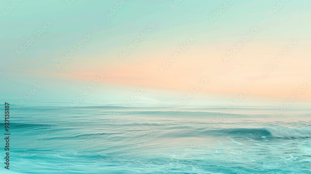 Fototapeta premium The image captures a serene scene of the ocean at dawn. Soft, pale pink and blue hues color the sky as the sun rises, casting a gentle light on the rippling water below. The waves gently roll towards 