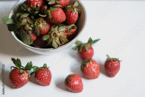 Heap of fresh strawberries in white ceramic bowl on rustic white background, fresh fruits.