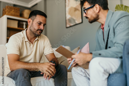 Young man having counseling with mental health professional in the bright living room