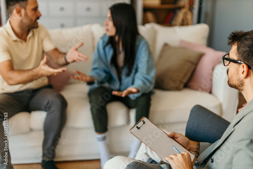 Man and woman sitting on couch and talking while psychologist listening to them