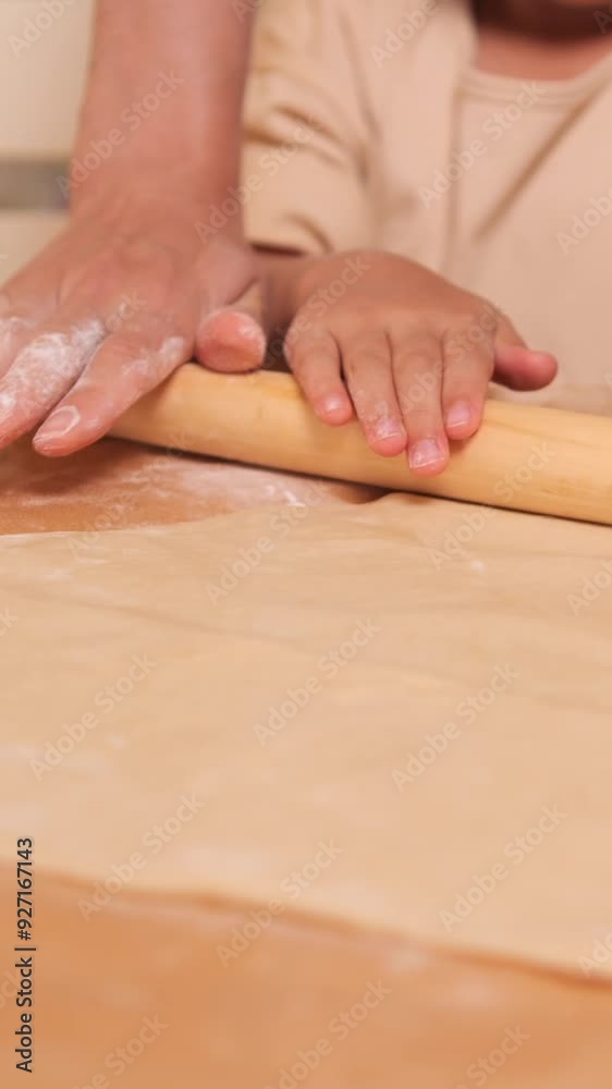 vertical video Young girl rolling dough on kitchen table with rolling pin