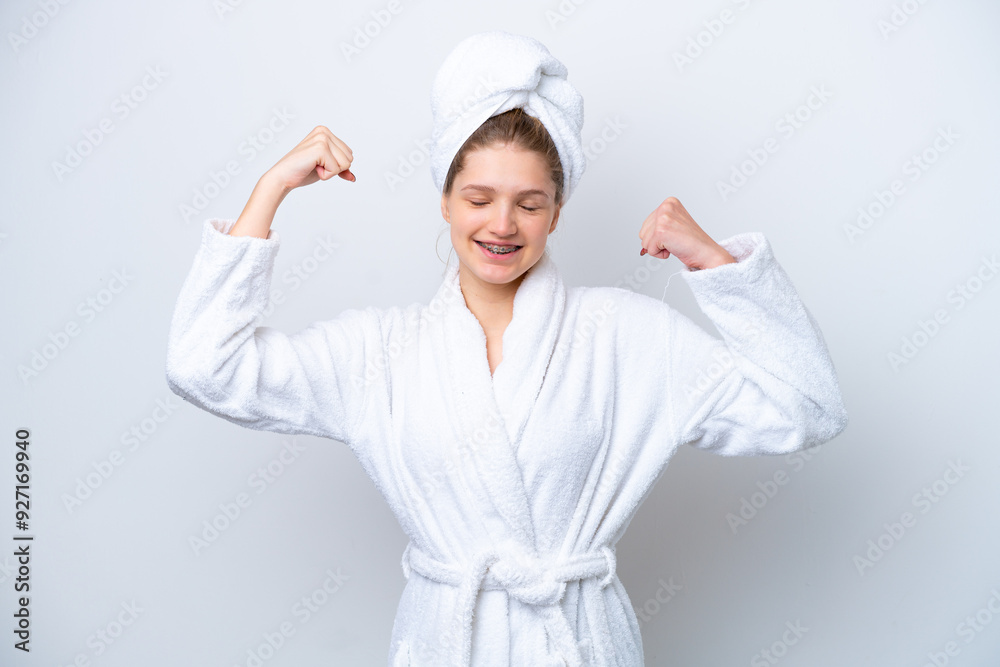 Teenager Russian girl in a bathrobe isolated on white background doing strong gesture Teenager Russian girl in a bathrobe isolated on white background doing strong gesture