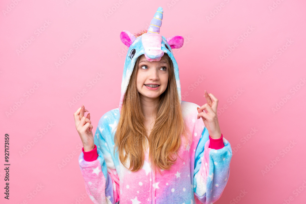 Teenager Russian girl with unicorn pajamas isolated on pink background with fingers crossing Teenager Russian girl with unicorn pajamas isolated on pink background with fingers crossing