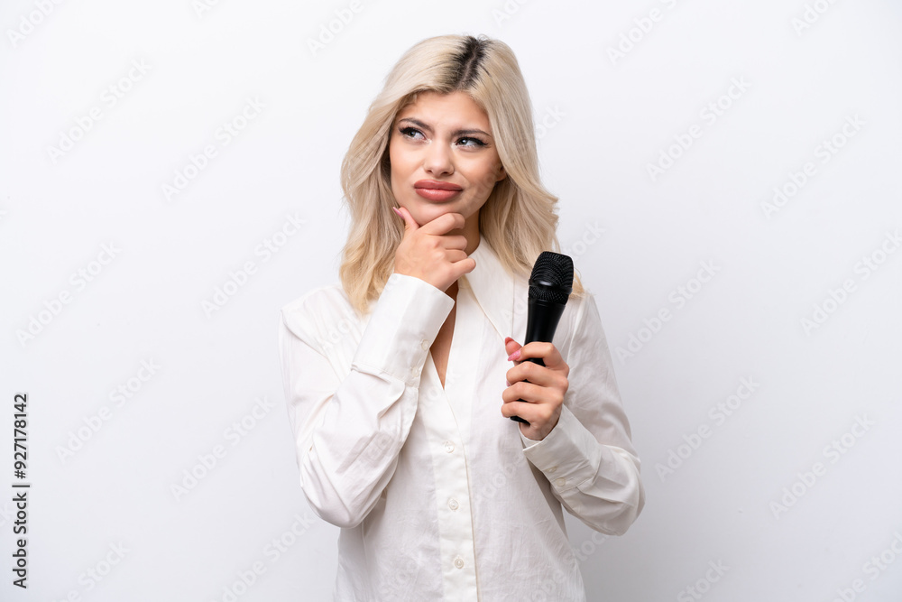 Young singer woman picking up a microphone isolated on white background having doubts Young singer woman picking up a microphone isolated on white background having doubts