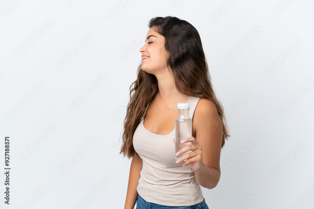 Young caucasian woman with a bottle of water isolated on white background laughing in lateral position Young caucasian woman with a bottle of water isolated on white background laughing in lateral position