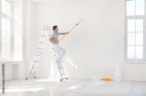 Schilderij op canvas Male painter or construction worker painting wall surface in white color with pa