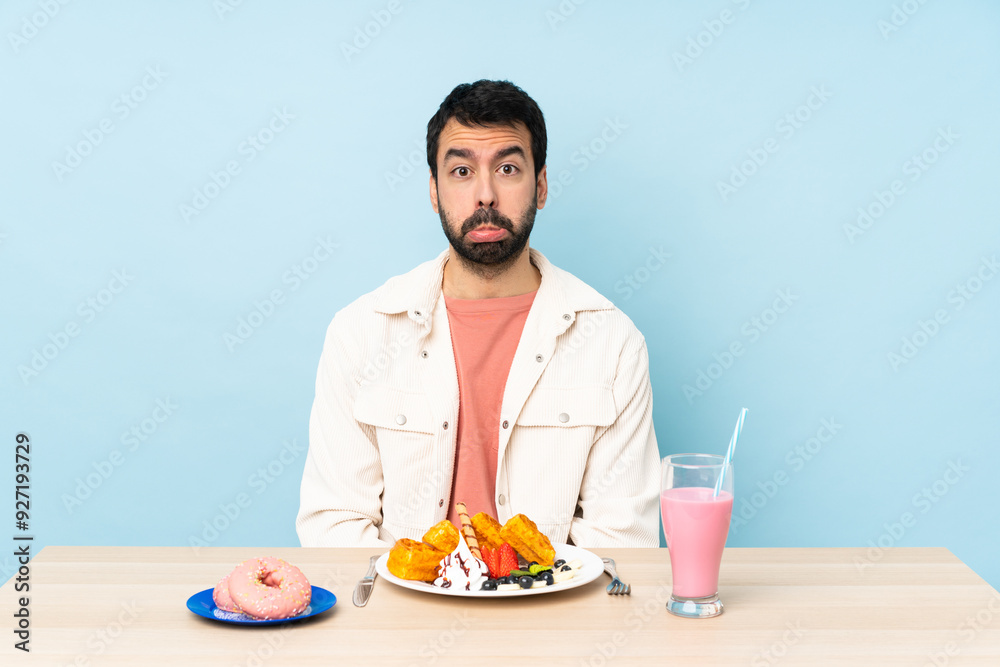 Man at a table having breakfast waffles and a milkshake with sad and depressed expression Man at a table having breakfast waffles and a milkshake with sad and depressed expression