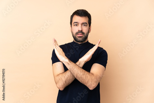 Caucasian handsome man over isolated background making NO gesture photo