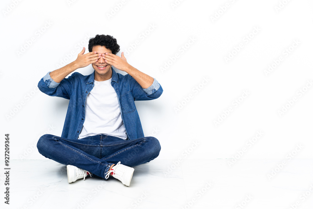 Venezuelan man sitting on the floor covering eyes by hands Venezuelan man sitting on the floor covering eyes by hands
