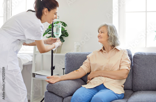 Senior woman with intravenous drip sitting on couch, physician, nurse doctor fixing IV drip infusion, geriatrics hospital eldercare, therapy to infuse vitamins, chemotherapy to maintain health clinic photo