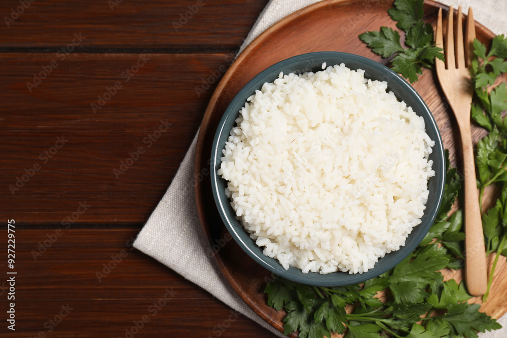 Delicious boiled rice served with parsley on wooden table, top view. Space for text Delicious boiled rice served with parsley on wooden table, top view. Space for text