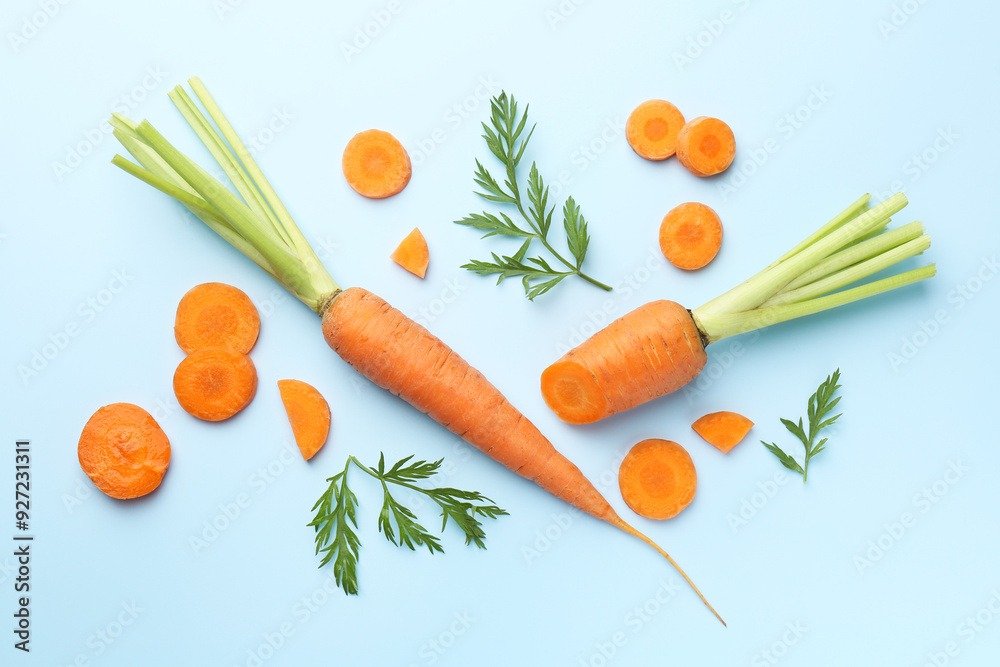 Whole and cut fresh carrots with green leaves on light background, flat lay Whole and cut fresh carrots with green leaves on light background, flat lay