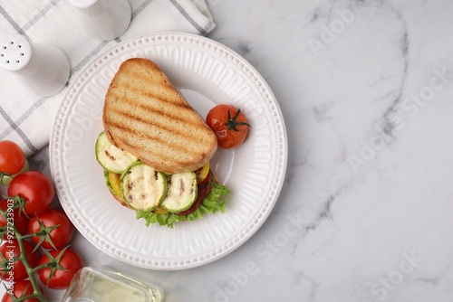 Tasty sandwich with grilled vegetables, fresh tomato and spices on white marble table, flat lay. Space for text photo