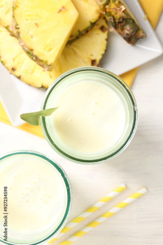 Tasty pineapple smoothie in glasses and fresh fruit on white wooden table, top view Tasty pineapple smoothie in glasses and fresh fruit on white wooden table, top view