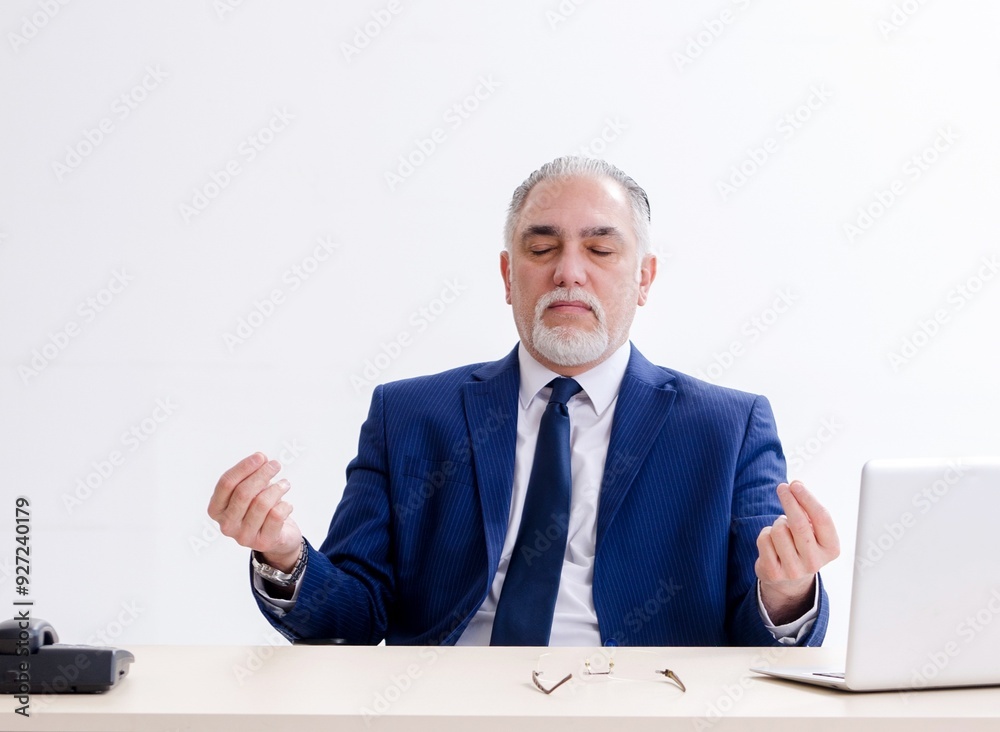 Aged businessman doing yoga exercises in the office Aged businessman doing yoga exercises in the office