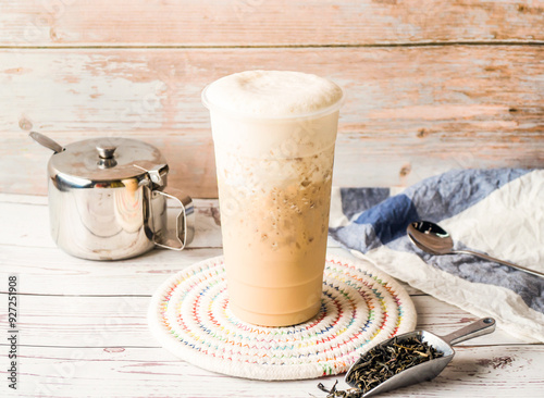 Iced Tieguanyin milk tea or Tie guan yin milk tea with sugar pot and spoon served in disposable glass isolated on table side view of hong kong tea photo