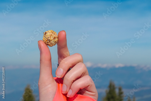 Obraz na płótnie Female hand holding a small, round energy ball Giotto filled with chocolate