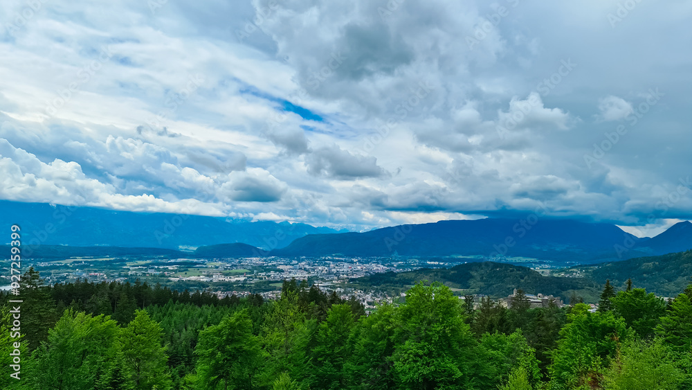 Panoramic aerial view of the city of Villach surrounded by majestic mountain ranges of Julian Alps and Karawanks, Carinthia, Austria, Europe. Idyllic forest walk near the Landskron Castle. Cityscape. Panoramic aerial view of the city of Villach surrounded by majestic mountain ranges of Julian Alps and Karawanks, Carinthia, Austria, Europe. Idyllic forest walk near the Landskron Castle. Cityscape.