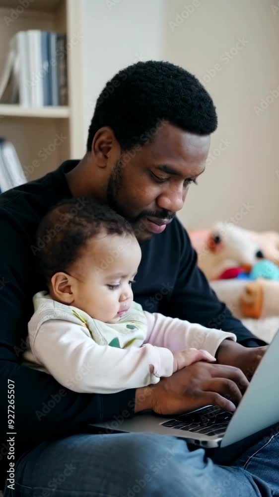 Young afro father working on a laptop at office home, holding him young child in his arms. Young afro father working on a laptop at office home, holding him young child in his arms.