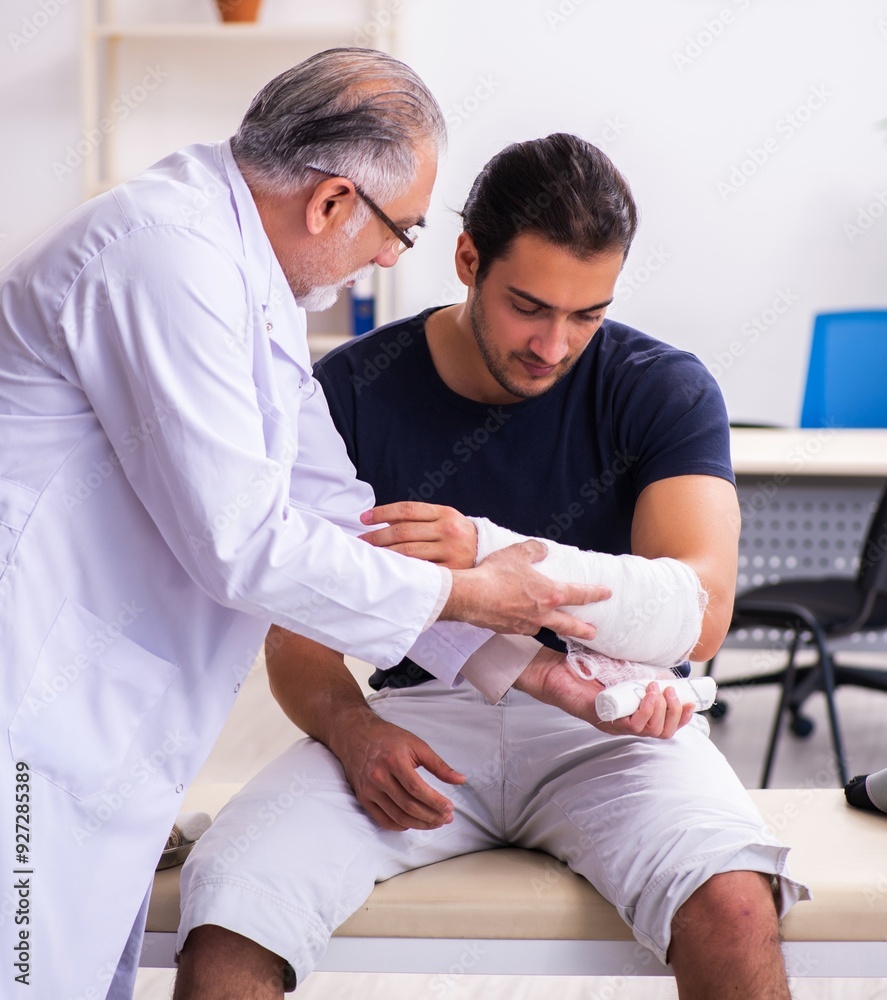 Young injured man visiting experienced male doctor traumatologis