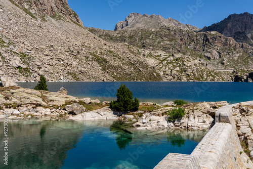 Mountain pond divided between mountains of stones and retaining wall