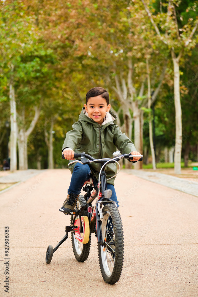 Latin five years old boy riding his bicycle in a park in a autumn day. Latin five years old boy riding his bicycle in a park in a autumn day.
