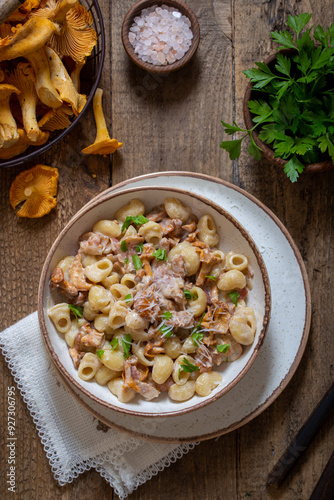 Pasta with chanterelles, bacon and cheese in plate on wooden table, top view, selective focus