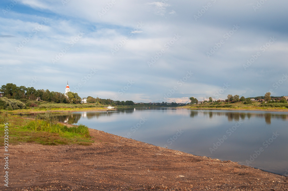 Obraz premium View of the Sukhona River in Totma town at sunset. The dome of an old church can be seen in the distance