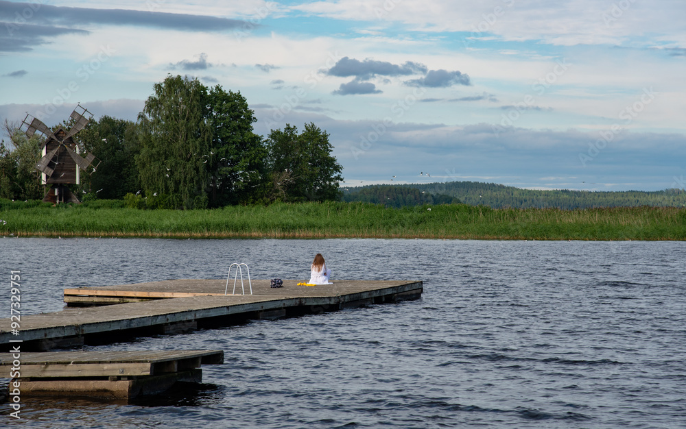 Calm meditation by the lake. Young woman sitting outdoors on the pier meditating . Calm relax mind. Calm meditation by the lake. Young woman sitting outdoors on the pier meditating . Calm relax mind.