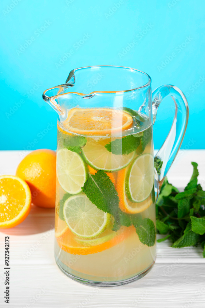 Fototapeta premium Freshly made lemonade with mint in jug on white wooden table against light blue background