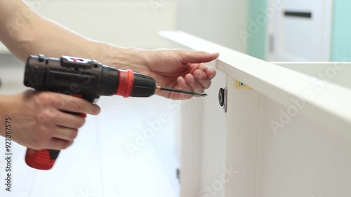 Wallpaper Mural A young craftsman assembles furniture fittings. Screwing the confirmat close-up. Professional furniture assembling. Installation of new furniture. Furniture assembly. 4k footage Torontodigital.ca
