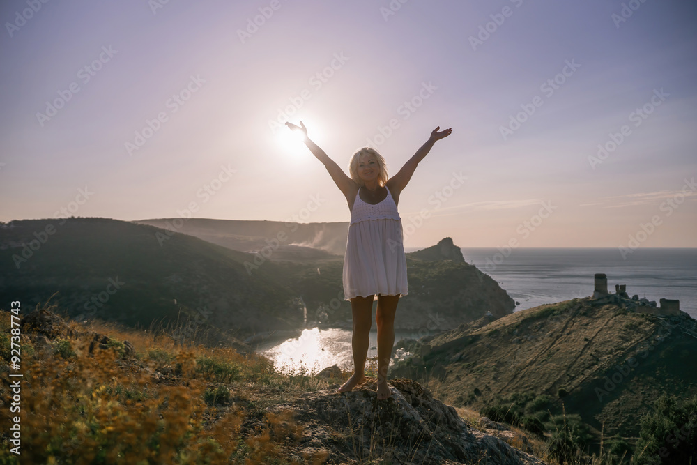 woman standing hill with her arms raised in the air, looking up at the sun. The scene is peaceful and serene, with the woman's expression conveying a sense of joy and happiness. woman standing hill with her arms raised in the air, looking up at the sun. The scene is peaceful and serene, with the woman's expression conveying a sense of joy and happiness.
