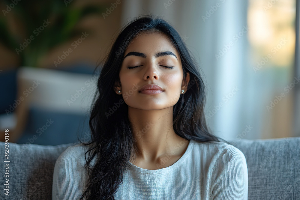 Close-Up of a Tranquil Indian Woman Meditating on a Couch: Yoga and Deep Breathing for Mental Health in a Cozy Home Environment Close-Up of a Tranquil Indian Woman Meditating on a Couch: Yoga and Deep Breathing for Mental Health in a Cozy Home Environment