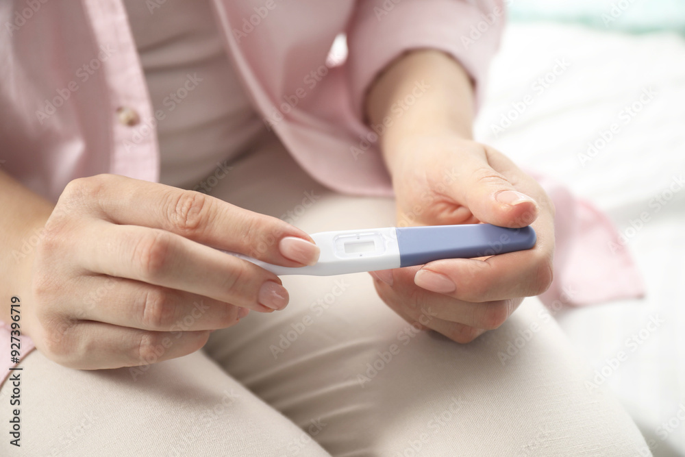 Woman holding pregnancy test indoors, closeup view Woman holding pregnancy test indoors, closeup view