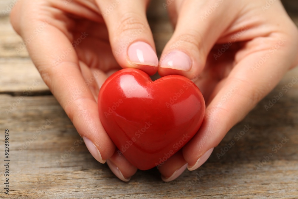 Woman with red decorative heart at wooden table, closeup Woman with red decorative heart at wooden table, closeup
