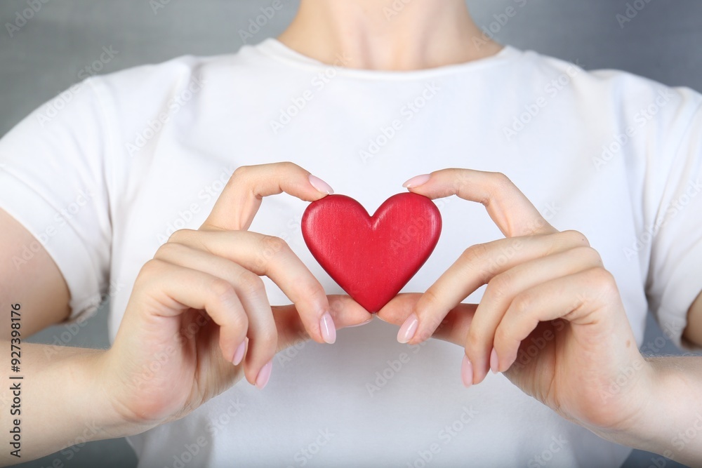 Woman holding red heart on grey background, closeup Woman holding red heart on grey background, closeup
